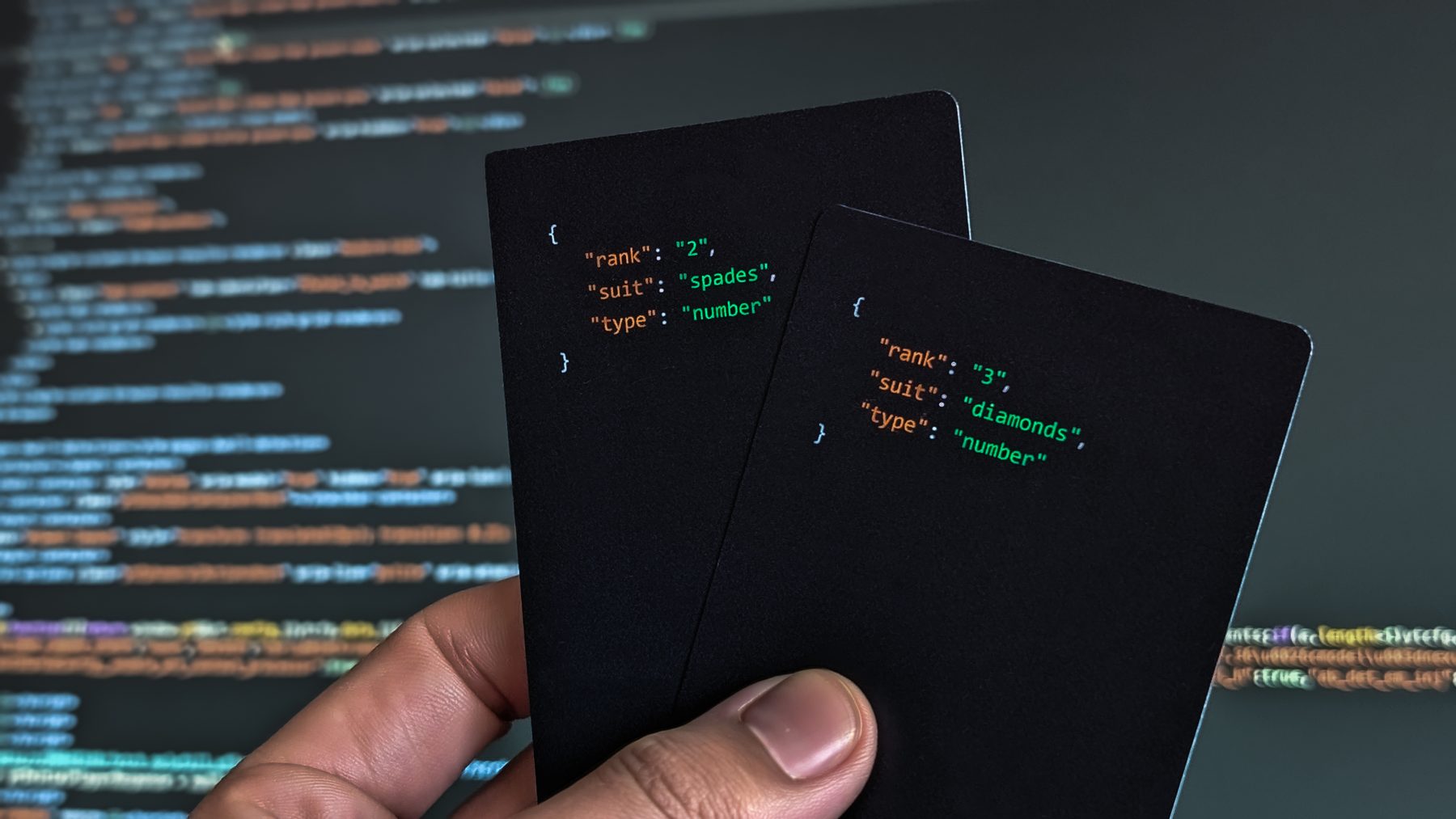 Two Pure Data playing cards held up in front of a computer screen